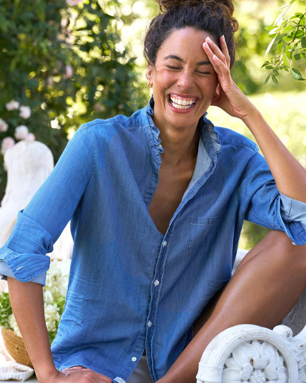 Woman wearing Frank & Eileen Eileen Ruffle in Vintage Stonewashed Indigo laughing outdoors with greenery in the background