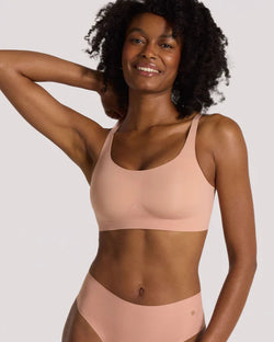 Woman wearing pink Evelyn & Bobbie Bobbie Scoop Bra in Himalayan Saltagainst a plain background