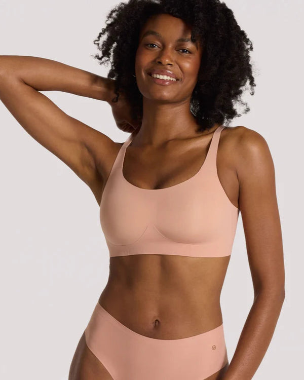 Woman wearing pink Evelyn & Bobbie Bobbie Scoop Bra in Himalayan Saltagainst a plain background