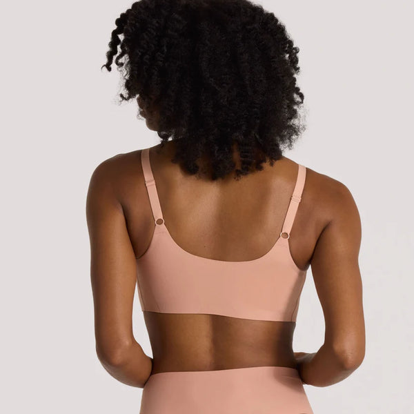 Woman wearing pink Evelyn & Bobbie Bobbie Scoop Bra in Himalayan Saltagainst a plain background backview