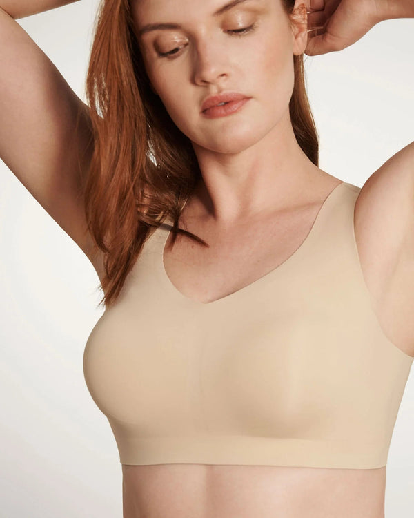 Woman wearing Evelyn & Bobbie Defy Bra in Sand against a plain background
