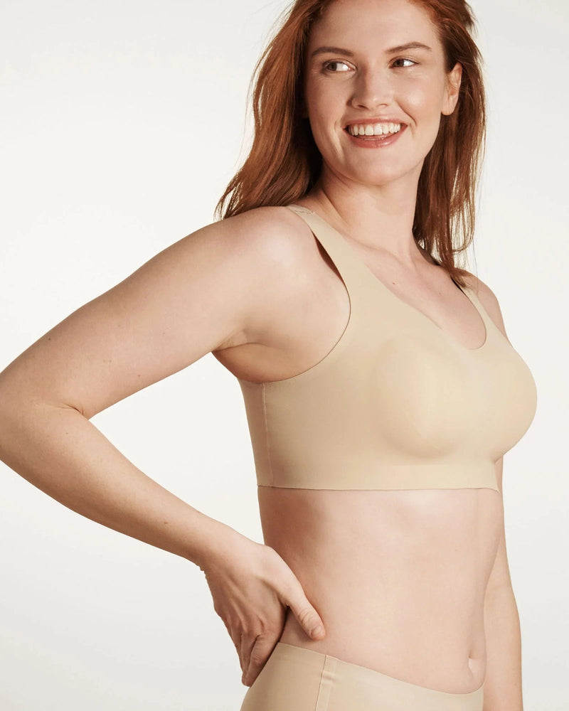 Woman wearing Evelyn & Bobbie Defy Bra in Sand against a plain background side view